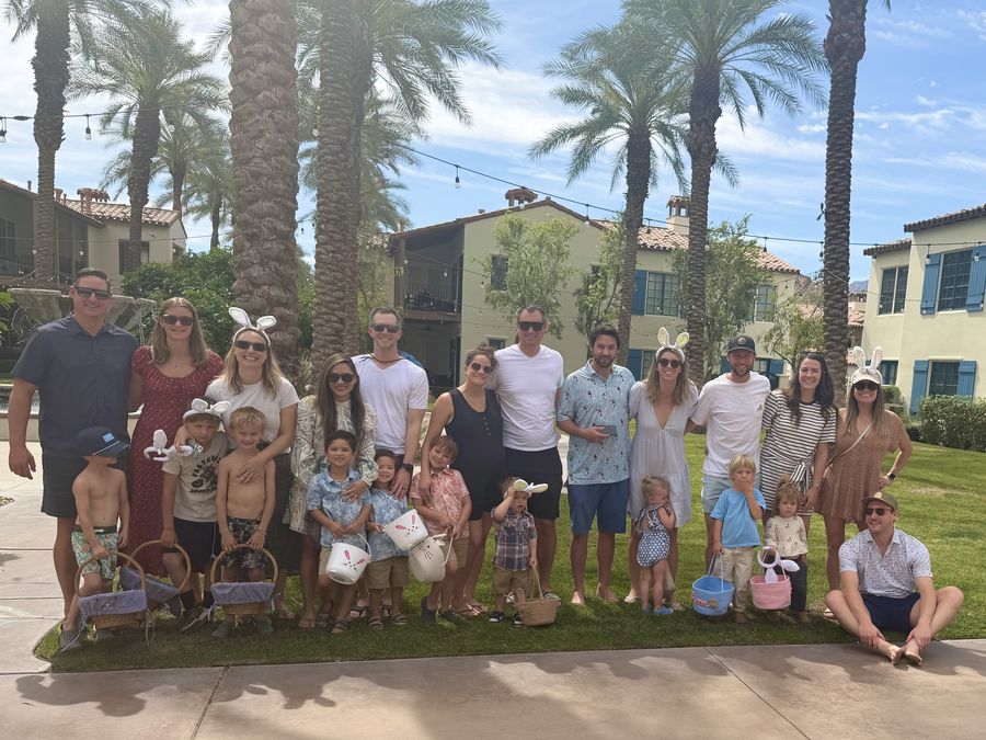 A multigenerational family gathered on a resort lawn under palm trees